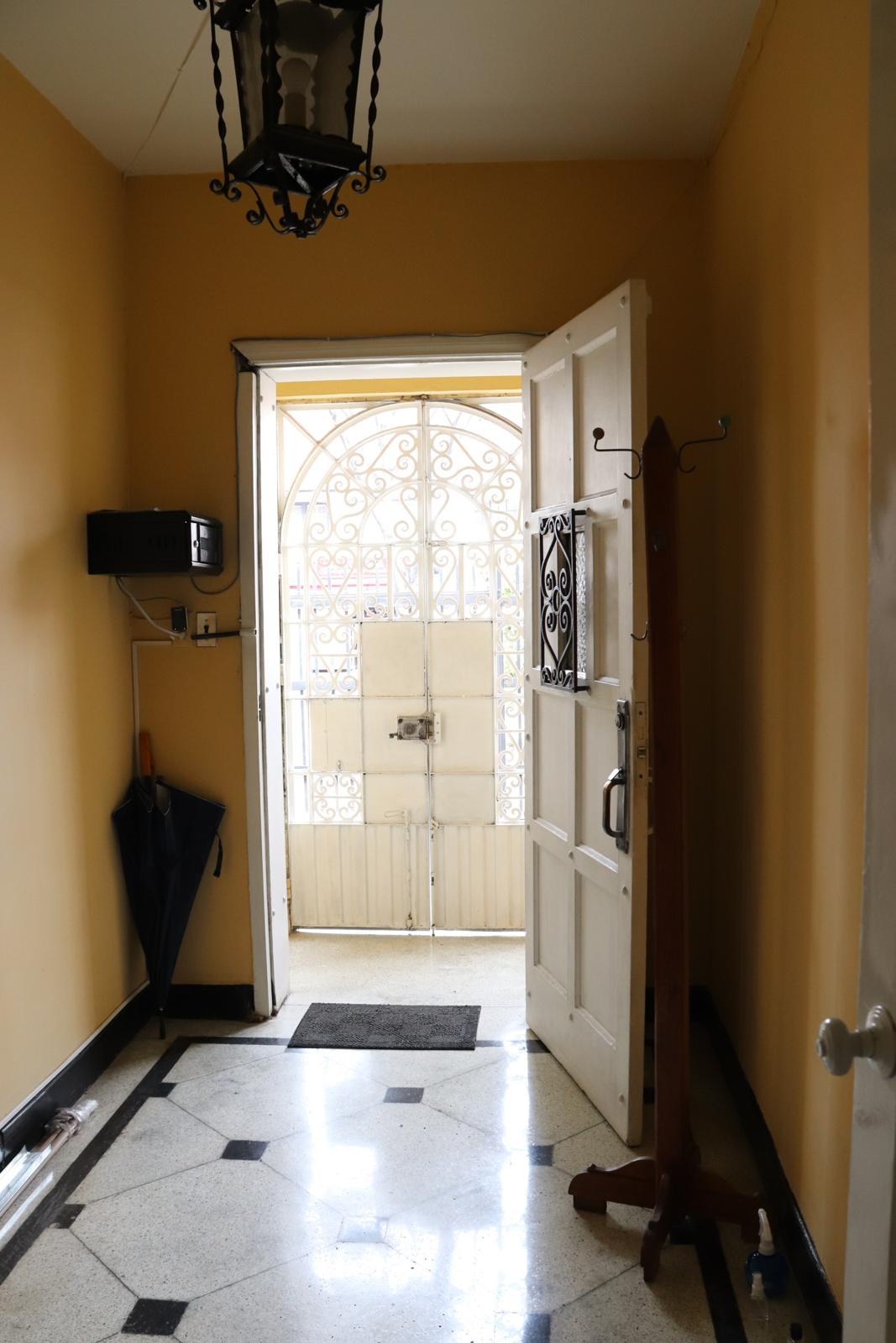 Entry hall with a black-and-white inlaid stone floor, iron lantern and wrought-iron front door