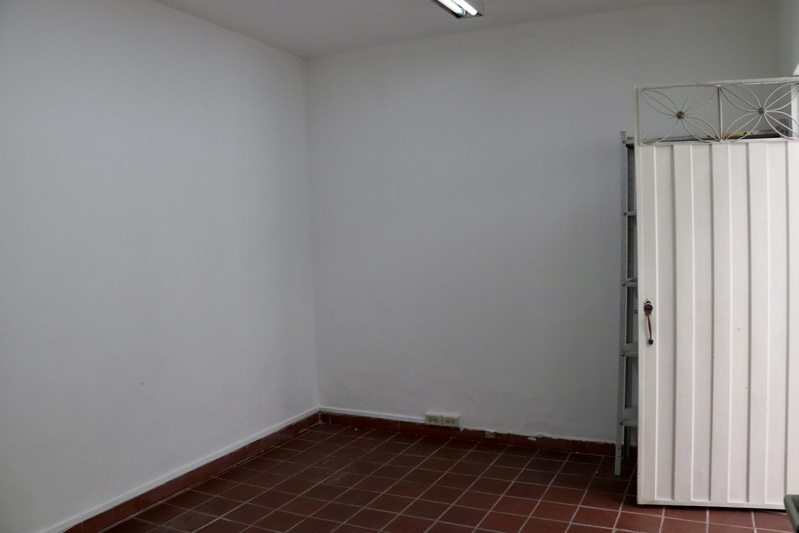 Empty room with a red clay-tile floor and a white metal door