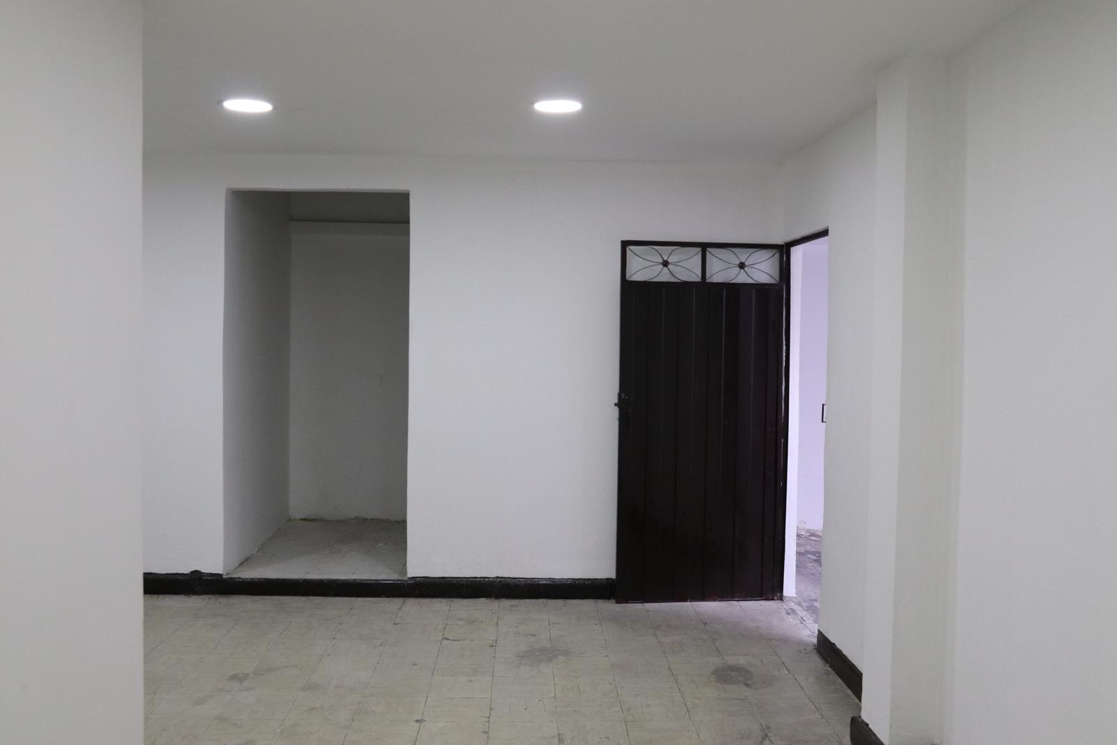 Empty room with a recessed niche and a dark metal door