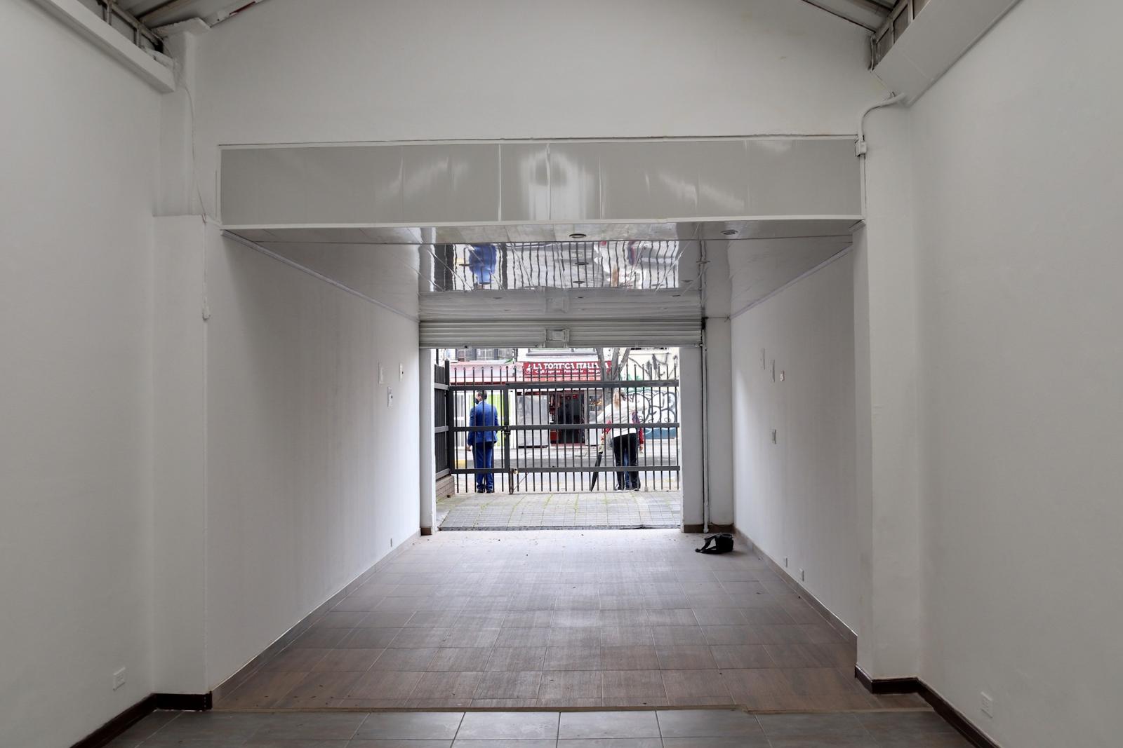 Long ground-floor space seen from inside, looking out through the shopfront gate to the street