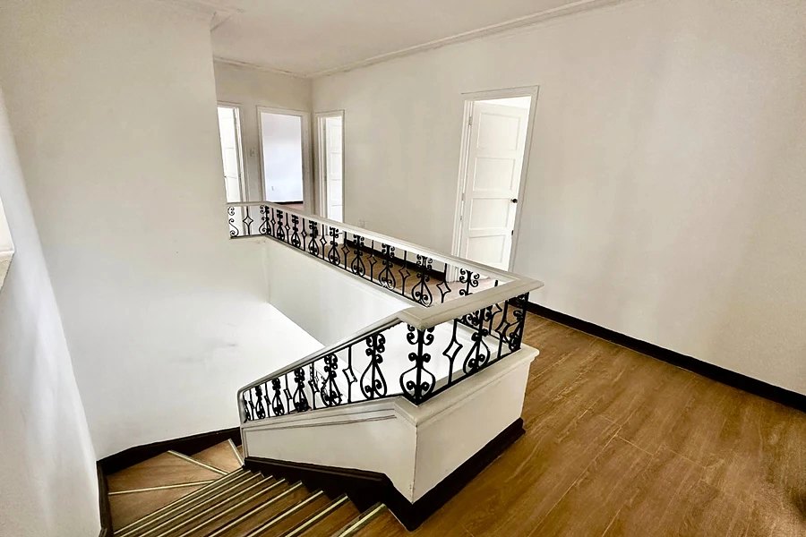 Upper-floor stair hall with a wrought-iron balustrade, wood-look floor and white doors